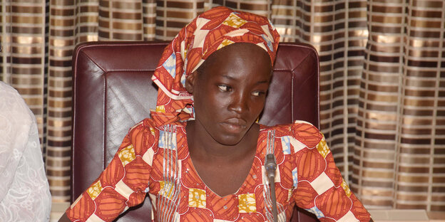 Amina Ali sitzt auf einem Stuhl und blickt betreten zur Seite Amina Ali sitzt auf einem Stuhl und blickt betreten zur Seite