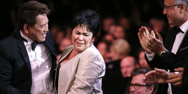Ein Mann und eine Frau stehen in einer applaudierenden Menge Ein Mann und eine Frau stehen in einer applaudierenden Menge