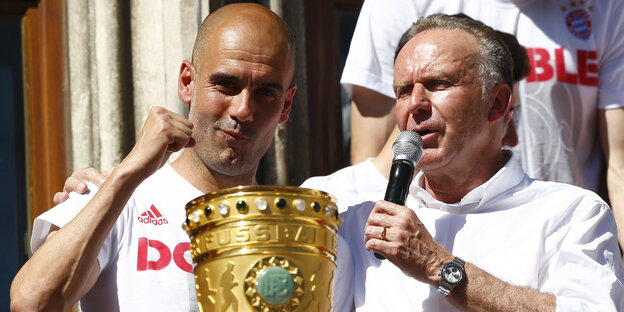 Rumenigge und Guardiola feiern mit DFB-Pokal. Rumenigge hält ein Mikrophon in der Hand Rumenigge und Guardiola feiern mit DFB-Pokal. Rumenigge hält ein Mikrophon in der Hand