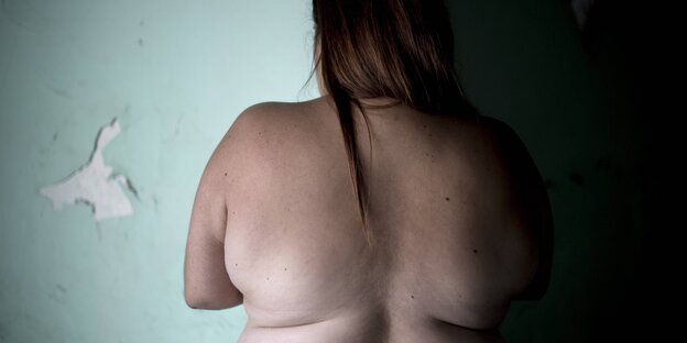 Rücken einer dicken Frau vor einer Wand Rücken einer dicken Frau vor einer Wand