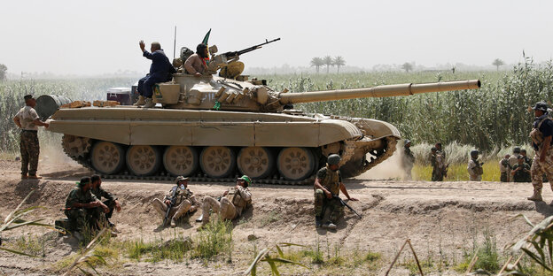 Ein Panzer und bewaffnet Uniformierte auf einem Sandweg Ein Panzer und bewaffnet Uniformierte auf einem Sandweg