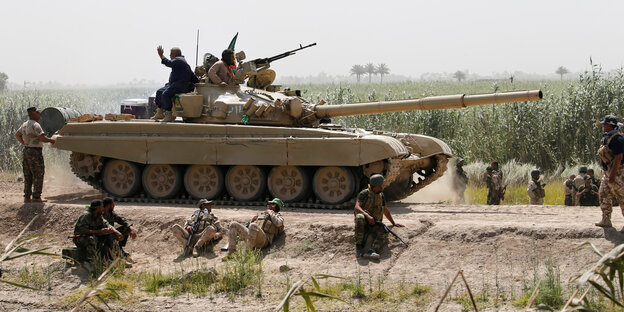 Ein Panzer und bewaffnet Uniformierte auf einem Sandweg