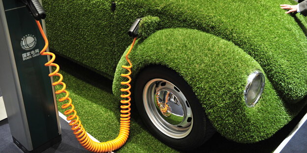 Ein mit Kunstrasen überzogener VW-Käfer an einer Elektrotankstelle Ein mit Kunstrasen überzogener VW-Käfer an einer Elektrotankstelle