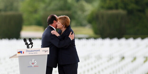 Angela Merkel und François Hollande umarmen sich vor vielen Reihen weißer Kreuze auf einem Soldatenfriedhof Angela Merkel und François Hollande umarmen sich vor vielen Reihen weißer Kreuze auf einem Soldatenfriedhof