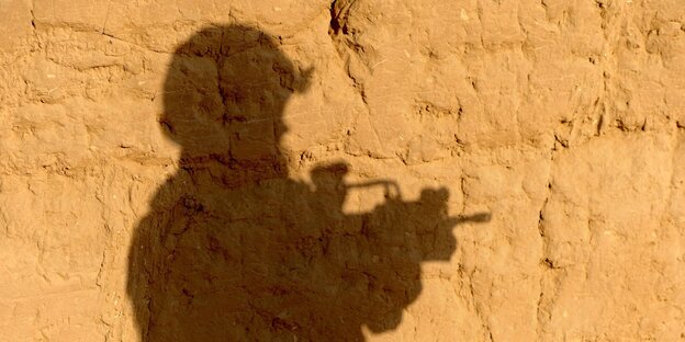 Der Schatten eines Soldaten auf einer lehmartigen Wand Der Schatten eines Soldaten auf einer lehmartigen Wand