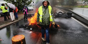 Ein Mann und brennende Reifen auf einer Straße