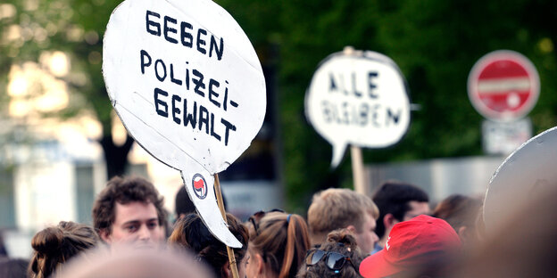 Menschen halten Schilder gegen Polizeigewalt hoch Menschen halten Schilder gegen Polizeigewalt hoch
