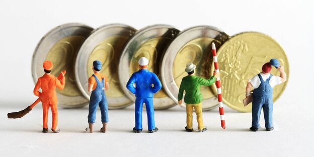 Kleine Plastikmännchen stehen vor vier Zwei-Euro-Münzen und einem Fünfzig-Cent-Stück Kleine Plastikmännchen stehen vor vier Zwei-Euro-Münzen und einem Fünfzig-Cent-Stück