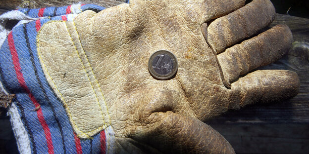 Auf einem Handschuh liegt ein Euro Auf einem Handschuh liegt ein Euro
