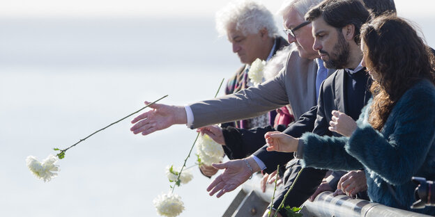 Frank-Walter Steinmeier und andere Menschen werfen weiße Rosen Frank-Walter Steinmeier und andere Menschen werfen weiße Rosen