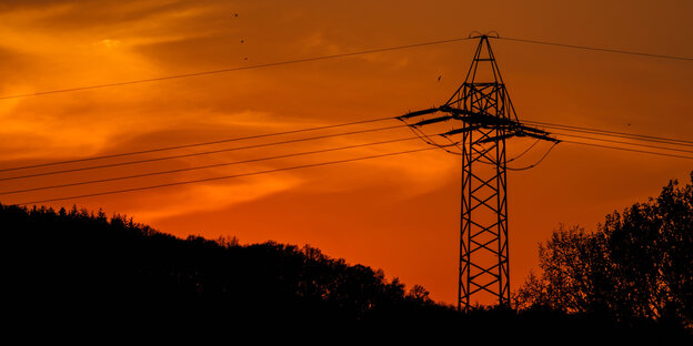 Ein Strommast gegen einen orange gefärbten Abendhimmel Ein Strommast gegen einen orange gefärbten Abendhimmel
