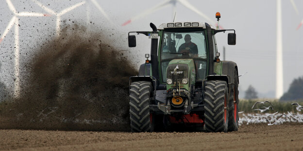 Ein Bauer wirbelt mächtig Erde in die Luft, während er mit seinem Traktor ein Feld bestellt Ein Bauer wirbelt mächtig Erde in die Luft, während er mit seinem Traktor ein Feld bestellt