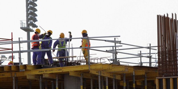 Mehrere Arbeiter stehen auf einer Baustelle in Katar Mehrere Arbeiter stehen auf einer Baustelle in Katar