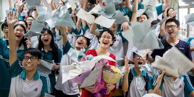 Chinesische Studenten jubeln und werfen Papiere in die Luft Chinesische Studenten jubeln und werfen Papiere in die Luft