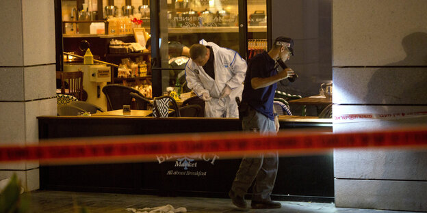 Zwei Männer untersuchen ein Restaurant, in dem ein Anschlag stattgefunden hat. Davor sieht man ein Absperrband Zwei Männer untersuchen ein Restaurant, in dem ein Anschlag stattgefunden hat. Davor sieht man ein Absperrband