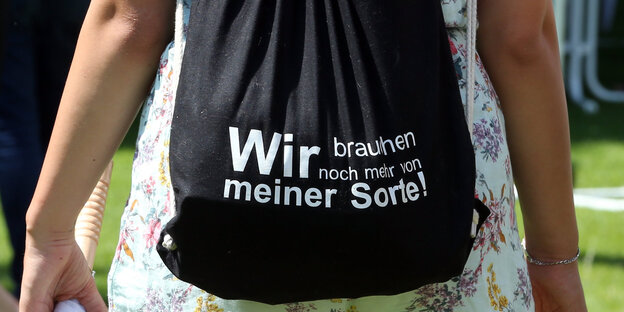 Ein Rucksack mit der Aufschrift: Wir brauchen noch mehr von meiner Sorte Ein Rucksack mit der Aufschrift: Wir brauchen noch mehr von meiner Sorte