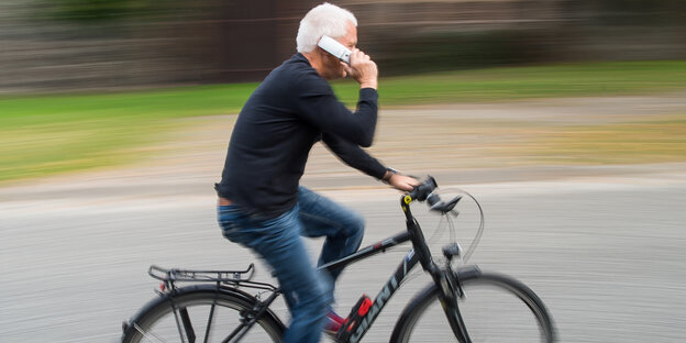 Ein Mann telefoniert auf dem Fahrrad Ein Mann telefoniert auf dem Fahrrad