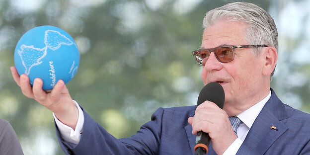 Bundespräsident Gauck mit Sonnenbrille hält im ausgestreckten linken arm eine kleine Weltkugel Bundespräsident Gauck mit Sonnenbrille hält im ausgestreckten linken arm eine kleine Weltkugel