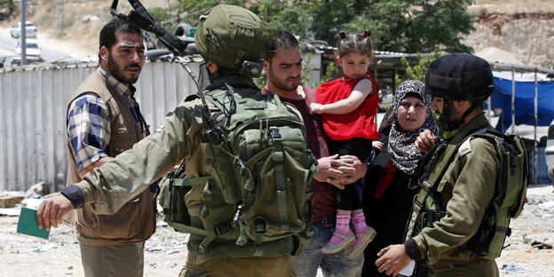 Zwei Soldaten sprechen mit einer Familie mit kleinen Kindern Zwei Soldaten sprechen mit einer Familie mit kleinen Kindern