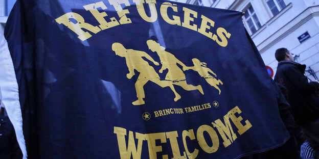 Eine dunkelblaue Flagge mit der gelben Aufschrift "Refugees Welcome" Eine dunkelblaue Flagge mit der gelben Aufschrift "Refugees Welcome"