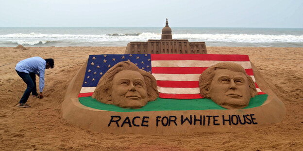 Ein Künstler an einer Sandburg mit den Gesichtern von Hillary Clinton und Donald Trump, der US-Flagge und dem Weißen Haus. Ein Künstler an einer Sandburg mit den Gesichtern von Hillary Clinton und Donald Trump, der US-Flagge und dem Weißen Haus.