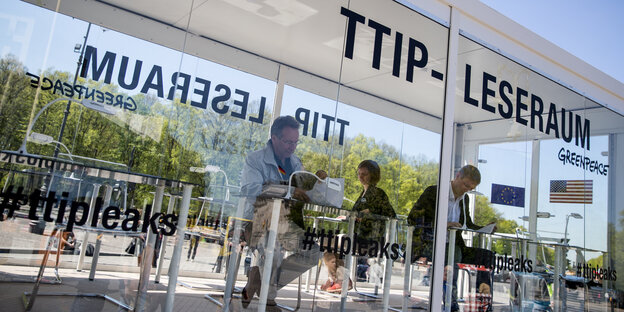 In einem Glaskasten mit der Aufschrift TTIP-Leseraum sitzen Menschen an Einzeltischen und blättern in Dokumenten. In einem Glaskasten mit der Aufschrift TTIP-Leseraum sitzen Menschen an Einzeltischen und blättern in Dokumenten.