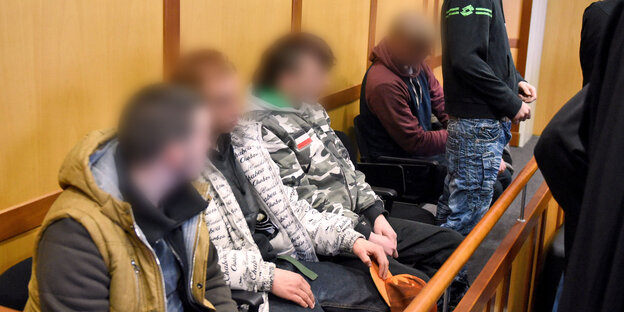 Vier junge Männer mit verpixelten Gesichtern sitzen auf einer Anklagebank, ein fünfter steht. Vier junge Männer mit verpixelten Gesichtern sitzen auf einer Anklagebank, ein fünfter steht.