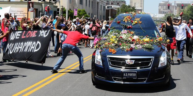 Menschen umringen einen mit Blumen bedeckten Leichenwagen bei der Trauerfeier für Muhammad Ali Menschen umringen einen mit Blumen bedeckten Leichenwagen bei der Trauerfeier für Muhammad Ali