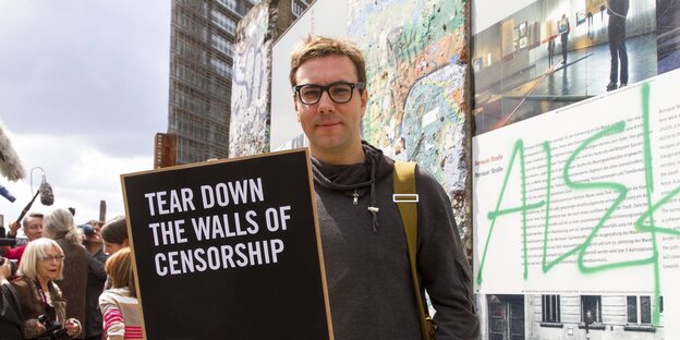 Mann mit Brille, es ist Jacob Appelbaum, mit einem Schild mit der Aufschrift "Tear down the walls of cenzorship" Mann mit Brille, es ist Jacob Appelbaum, mit einem Schild mit der Aufschrift "Tear down the walls of cenzorship"