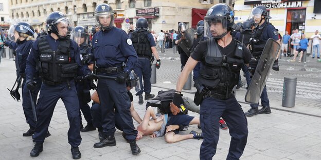 Polizisten in Kampfmontur in Marseille, im Hintergrund liegen Menschen am Boden Polizisten in Kampfmontur in Marseille, im Hintergrund liegen Menschen am Boden