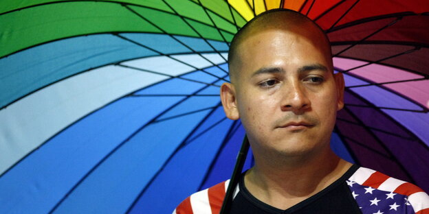 Ein Unterstützer der LGBTIQ-Community in Kolumbien ehrt die Opfer von Orlando und hält einen Schirm in Regenbogenfarben Ein Unterstützer der LGBTIQ-Community in Kolumbien ehrt die Opfer von Orlando und hält einen Schirm in Regenbogenfarben