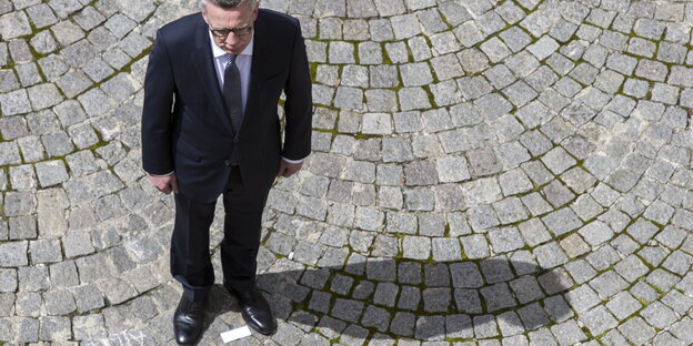 de Maizière auf Pflaster stehend von oben fotografiert de Maizière auf Pflaster stehend von oben fotografiert