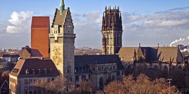 Duisburgs Rathaus im Vordergrund, im Hintergrund ein Kirchturm vor blauem Himmel