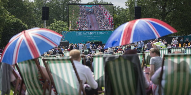 Mehrere Menschen sitzen im Park und feiern den 90. Geburtstag der britischen Königin Mehrere Menschen sitzen im Park und feiern den 90. Geburtstag der britischen Königin