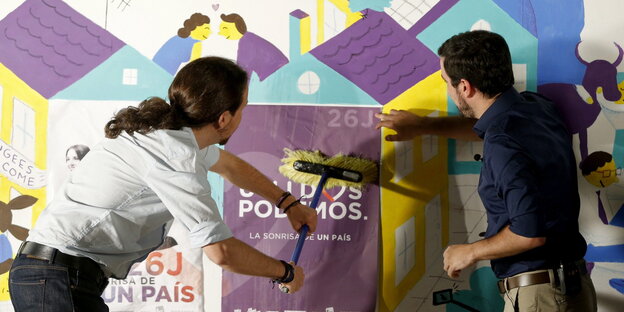 Zwei Männer kleben gemeinsam Plakate an die Wand, links zu sehen: der Podemos-Chef Pablo Iglesias Zwei Männer kleben gemeinsam Plakate an die Wand, links zu sehen: der Podemos-Chef Pablo Iglesias