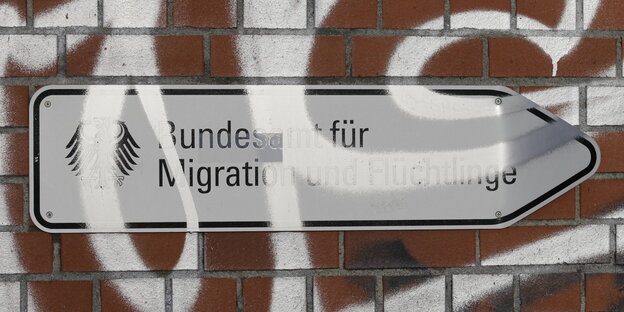 Auf einem Schild steht: "Bundesamt für MIgration und Flüchtlinge", darüber Graffiti Auf einem Schild steht: "Bundesamt für MIgration und Flüchtlinge", darüber Graffiti