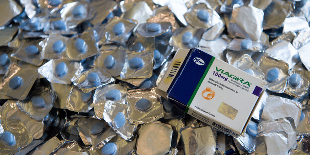 Verpackte blaue Pillen und eine Viagra-Packung Verpackte blaue Pillen und eine Viagra-Packung