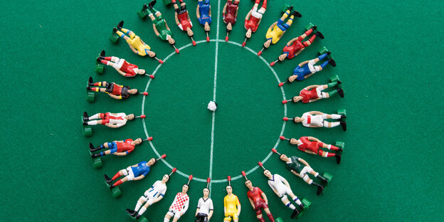 Viele Tipp-Kick-Figuren liegen auf einem Spielfeld. Alle sind weiße Männer. Viele Tipp-Kick-Figuren liegen auf einem Spielfeld. Alle sind weiße Männer.