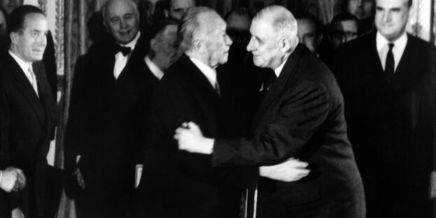 Ein schwarz-weiß Bild: Konrad Adenauer und Charles de Gaulle umarmen sich Ein schwarz-weiß Bild: Konrad Adenauer und Charles de Gaulle umarmen sich