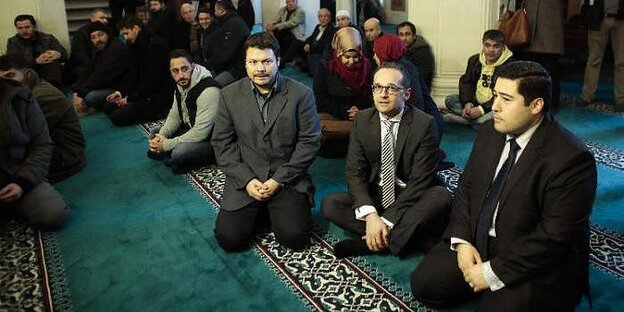 Ender Cetin kniet neben Justizminister Heiko Maas in der Sehitlik-Moschee Ender Cetin kniet neben Justizminister Heiko Maas in der Sehitlik-Moschee