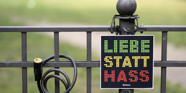 An einem Zaun hängt ein Schild „Liebe statt Hass“ An einem Zaun hängt ein Schild „Liebe statt Hass“