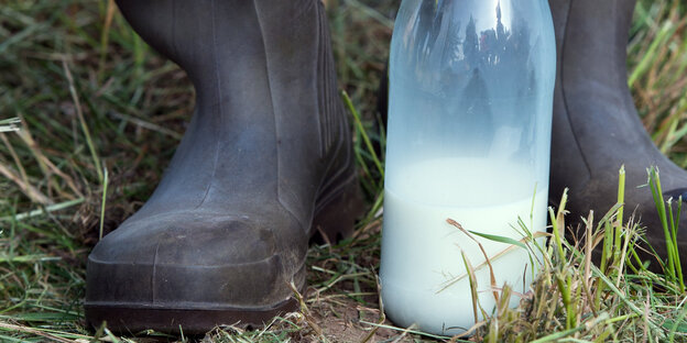 Eine Milchflasche zwischen Gummistiefeln Eine Milchflasche zwischen Gummistiefeln