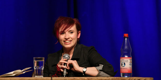 Eine Frau sitzt an einem Tisch. Es ist Laurie Penny Eine Frau sitzt an einem Tisch. Es ist Laurie Penny
