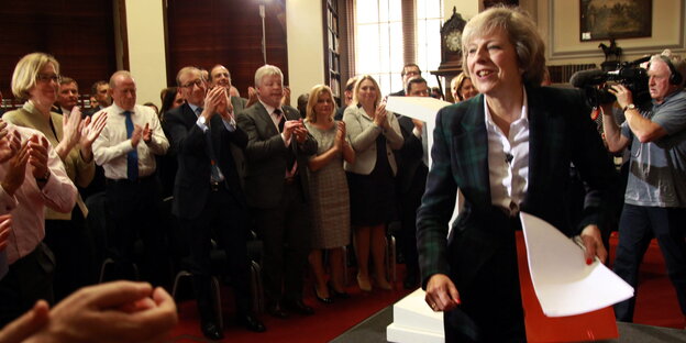 Theresa May in einem Raum mi Menschen, die ihr applaudieren Theresa May in einem Raum mi Menschen, die ihr applaudieren