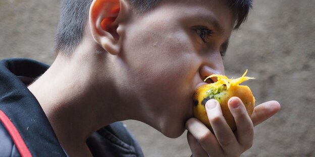 Ein Junge beißt in eine Mango Ein Junge beißt in eine Mango