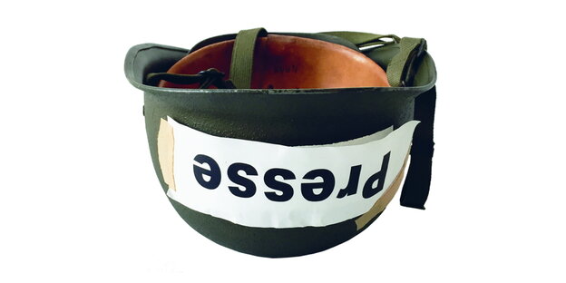 Ein umgedrehter Militärhelm, auf dem Presse steht Ein umgedrehter Militärhelm, auf dem Presse steht