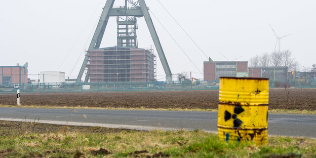 Förderturm eines Bergwerkes, im Vordergrund ein gelbes Fass mit Strahlenwarnzeichen Förderturm eines Bergwerkes, im Vordergrund ein gelbes Fass mit Strahlenwarnzeichen
