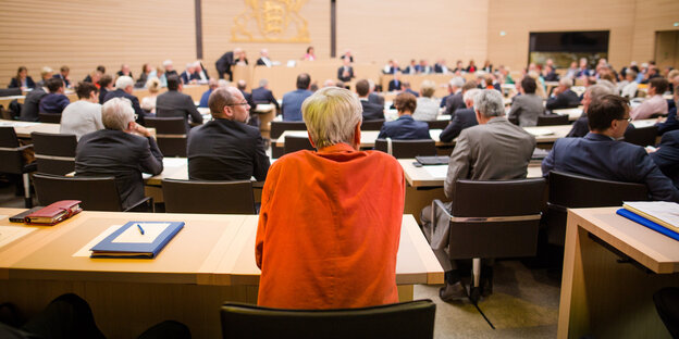 Menschen sitzen an Tischen in einem Saal