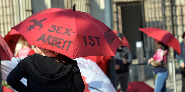 Menschen mit Regenschirmen, auf einem steht „Sexarbeit ist Arbeit“ Menschen mit Regenschirmen, auf einem steht „Sexarbeit ist Arbeit“