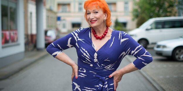 Eine Frau stützt die Hände in die Hüfte und lächelt Eine Frau stützt die Hände in die Hüfte und lächelt
